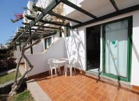 Bungalow mit kleinem, grünem Garten und Terrasse.